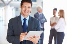 A man in suit and tie holding a tablet.